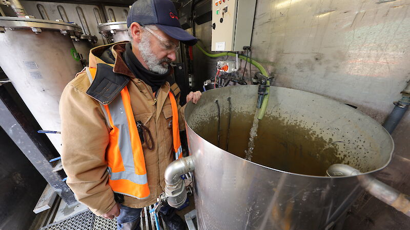 A man watches water fall into a vat