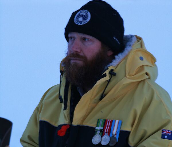 Close up of bearded man, wearing AAD beanie and goose down jacket, wearing service medals and red poppy.