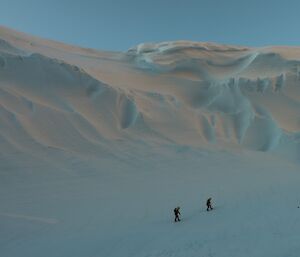 Large ice wind scour with two expeditioners moving across the base