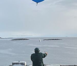 A person letting off a large blue weather balloon into the sky