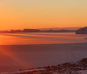 An orange sunset over sea ice