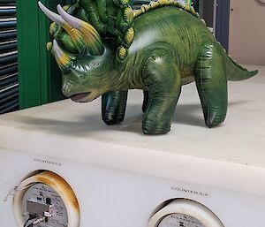 Inflatable triceratops toy stands on science equipment - housing for cosmic ray tubes