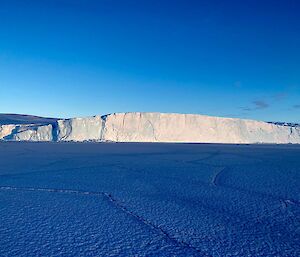 view across sea ice to ice cliffs in the distance