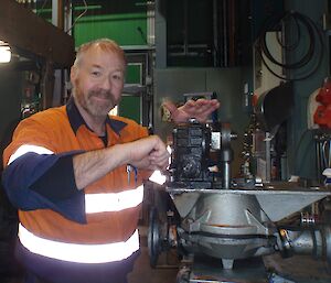 A man in hi vis repairs a pump in a workshop