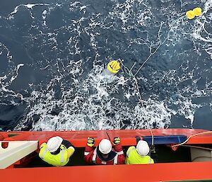 looking down on crew attaching rope to floating equipment