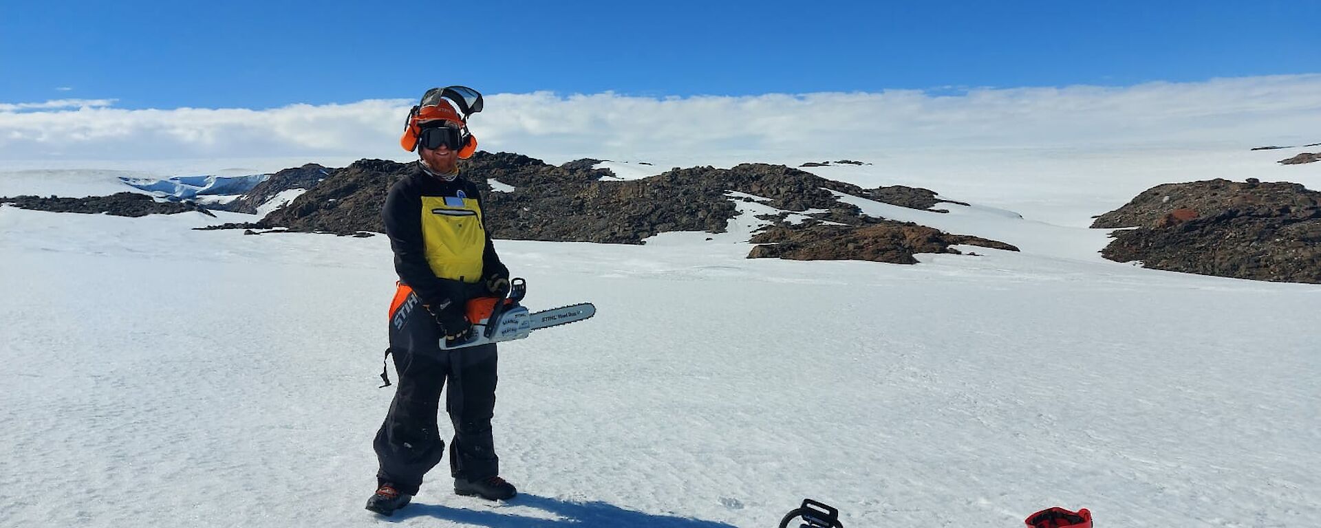 A man standing on the ice with a chainsaw