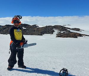 A man standing on the ice with a chainsaw