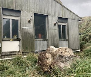 A large rock sits near a wooden building