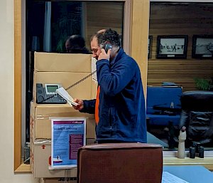 Man stands on phone in polling booth made from cardboard boxes