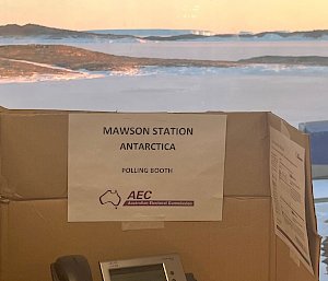 Polling booth (made of carboard box) in foreground with view of sea ice and island in the background