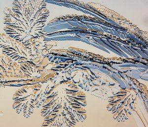 A magnified photo of ice crystals formed on a window, in a splayed structure similar to palm fronds, capturing the colours of the sky outside with blue shadows and gold highlights