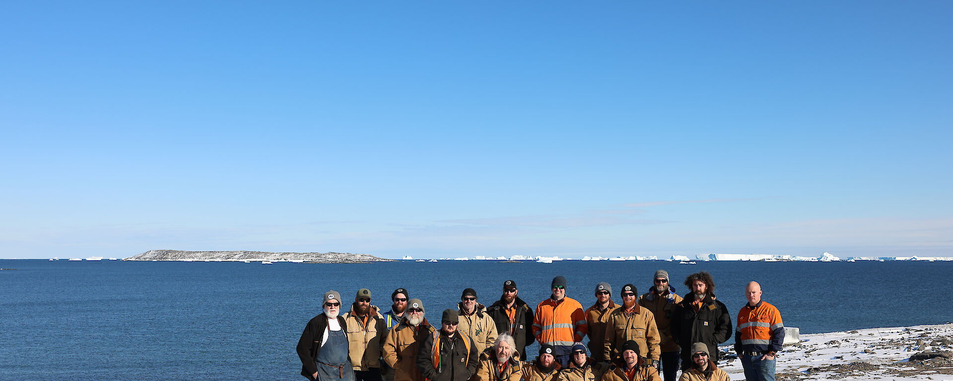 A group of expeditioners standing in front of the ocean on snow