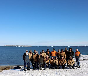 A group of expeditioners standing in front of the ocean on snow