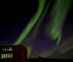 A green aurora lights up the sky over the station's buildings