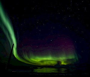 A green aurora lights up the sky over the station's buildings