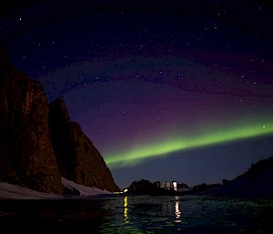 A green aurora lights up the sky over the station's buildings