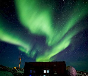 A green aurora lights up the sky over the station's buildings