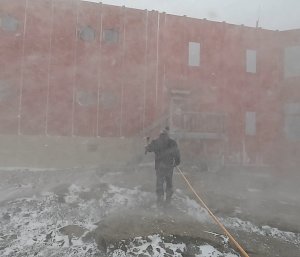 Person with snow whipping around them holding onto blizz line as they walk away from the photographer towards the RedShed