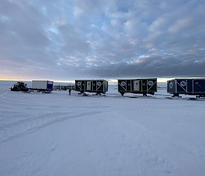 A series of rectangular cabins mounted on skis, hitched together to be towed by tractor across the snow