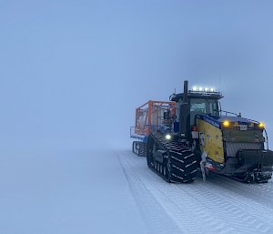 A Challenger tractor towing a flatbed. The cloudy sky appears to merge seamlessly with the snowy ground