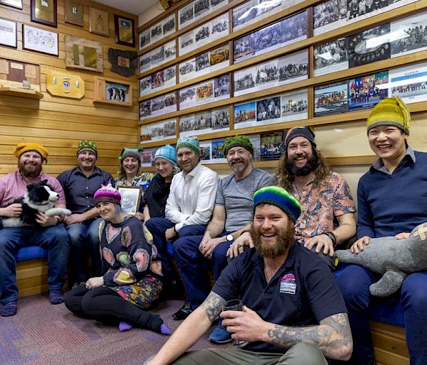 A group of people wearing colourful beanies and holding plush toys