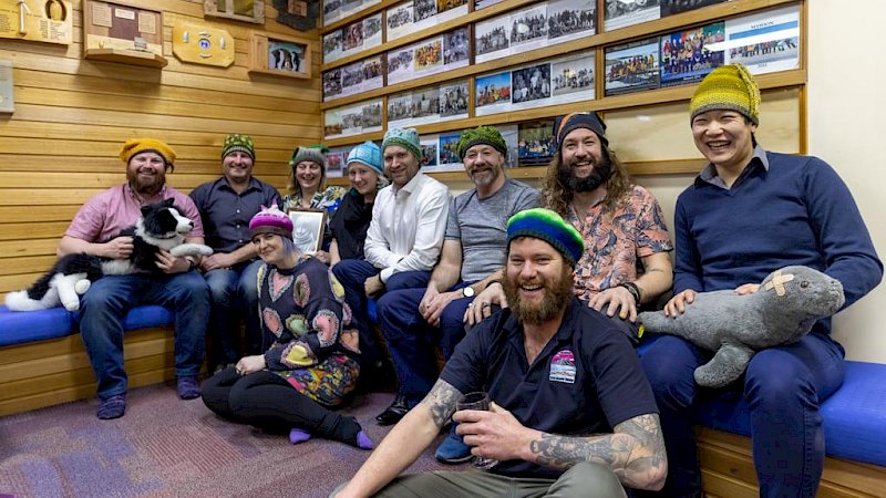 A group of people wearing colourful beanies and holding plush toys