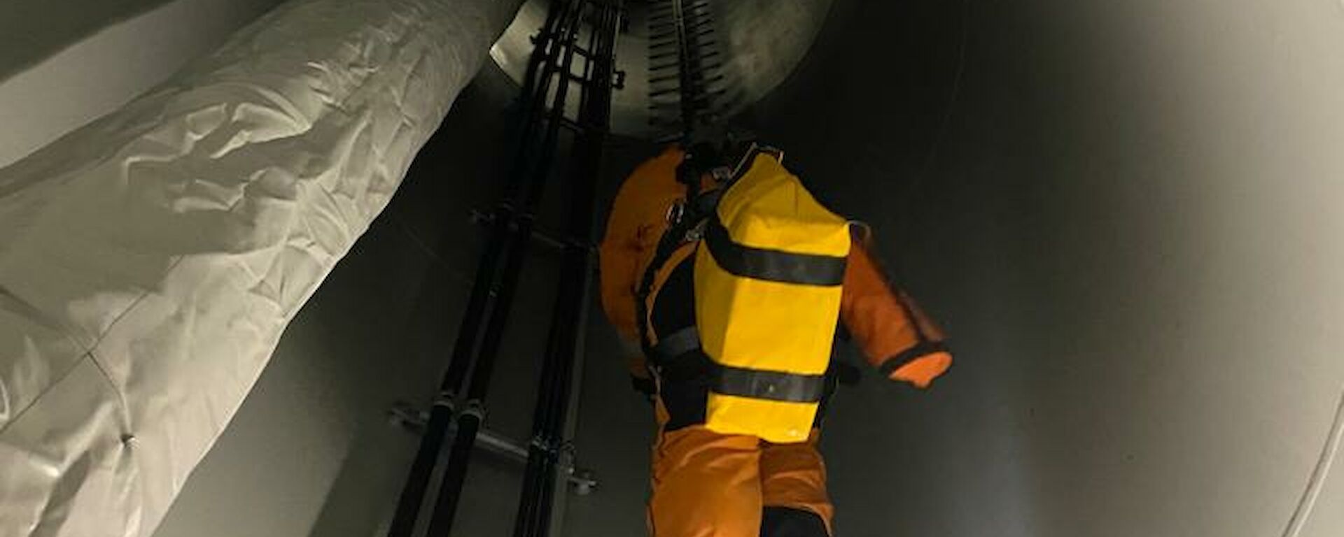 Looking up the inside of the wind turbine at ladder and expeditioner climbing up ahead