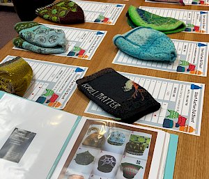 Ten hats with silent auction sheets underneath laid out on table