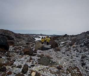 A group of expeditioners in the distance on rocks and snow