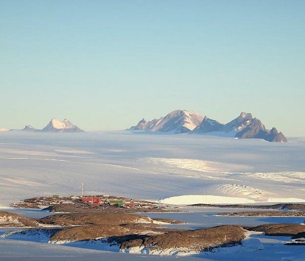 Ice plateau and mountain range in distance, mid distance is the station on the edge of the water