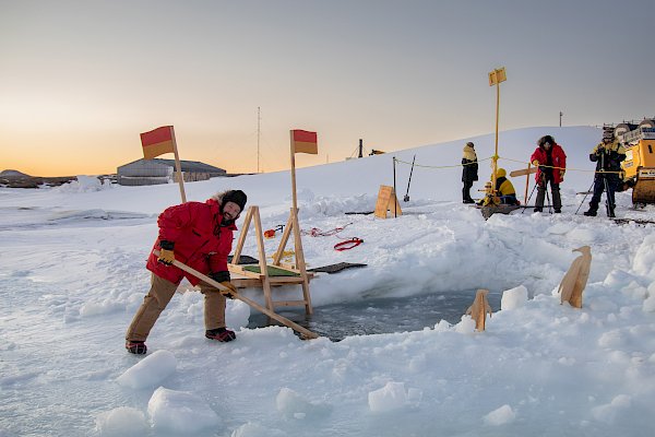 A man sculpts a hole in the ice for swimming