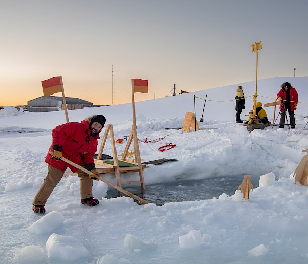 A man sculpts a hole in the ice for swimming