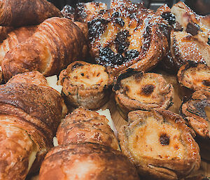 Close up of assorted pastries, croissants, Portuguese tarts and Danishes