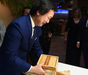 Man in suit opens gift containing wooden box