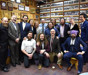 Group photo of 15 people, all wearing semi-formal wear, facing camera and smiling