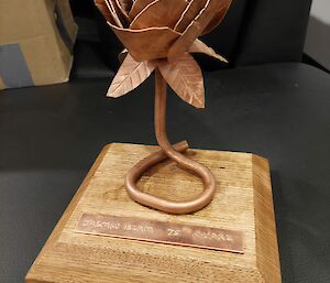 A hand-crafted metal flower mounted on a wooden stand