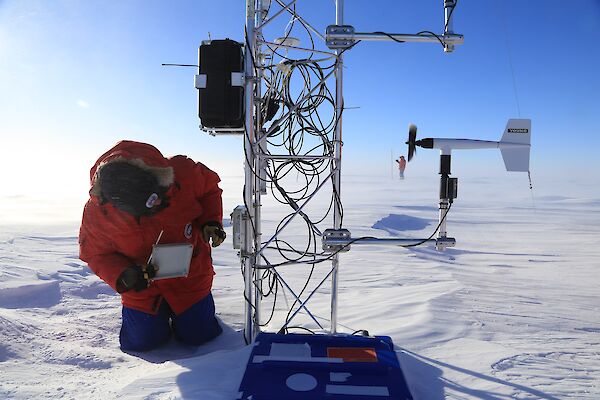 person checks mast with coiled cables on snowy ice