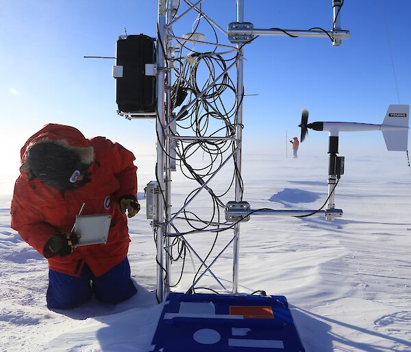 person checks mast with coiled cables on snowy ice