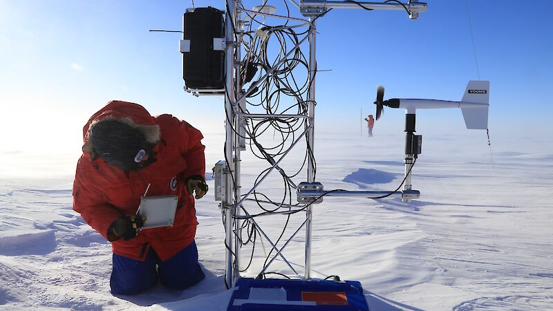 person checks mast with coiled cables on snowy ice