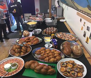 A couple of people stand at a table full of food