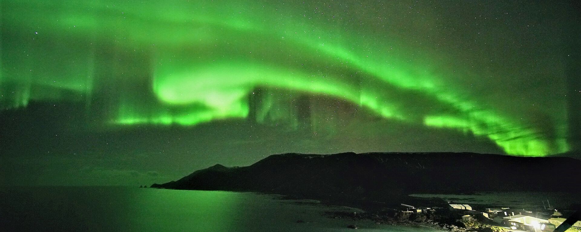 An bright green aurora lights up the station and part of  the island