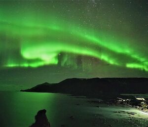 An bright green aurora lights up the station and part of  the island