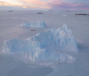Picture taken from a drone showing tiny hagglunds amongst two large icebergs