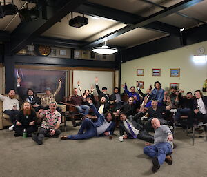 The Davis winter group sitting on the floor and lounge area with arms in the air