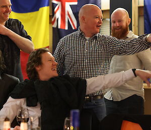 A group of 5 people laughing and and pointing with an array of flags in the background
