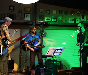 Three people playing in a band on stage