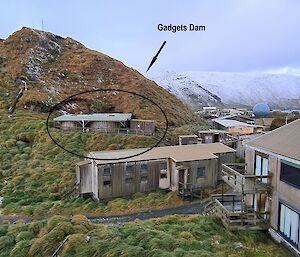 Some buildings near a hill with water tanks on it