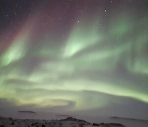 A green and purple aurora over snow
