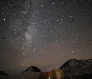 Night, small hut in background, large expanse of sky with milky way