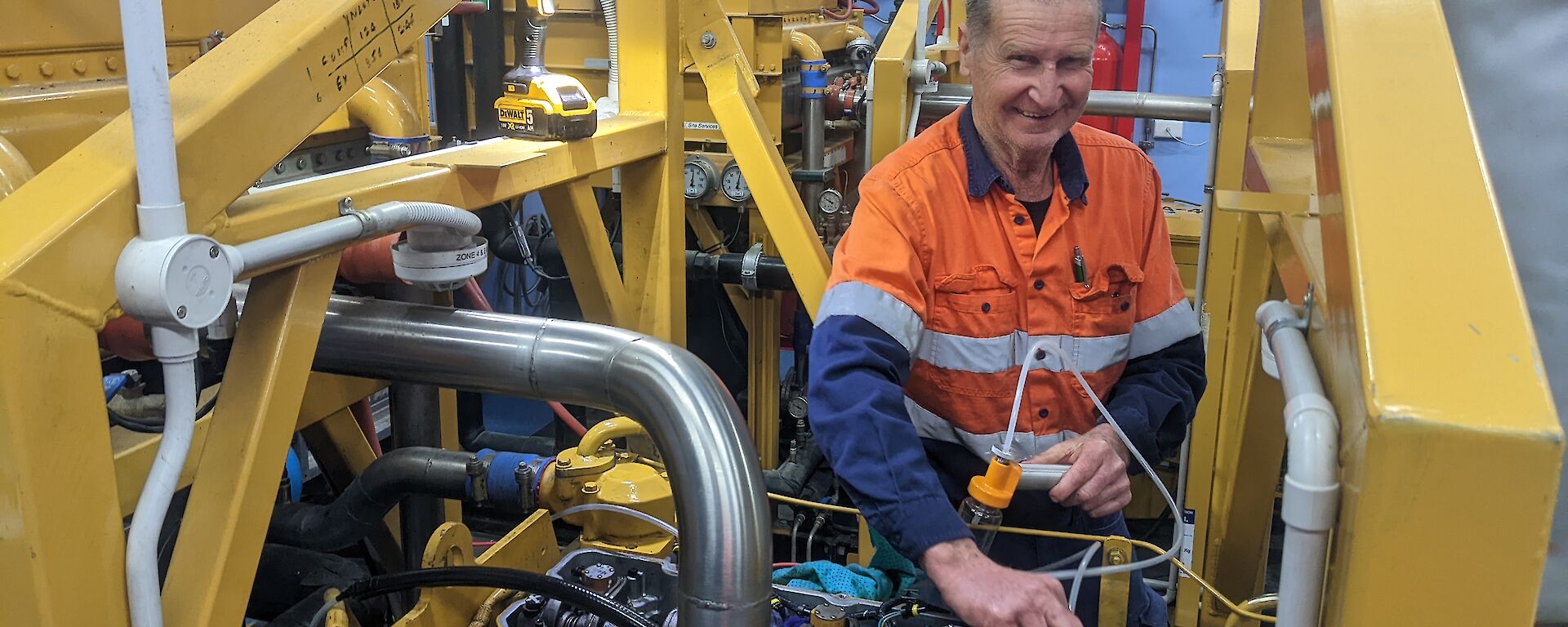 A man in hi viz works on a yellow generator
